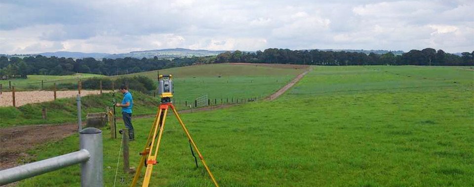 Members of the Vector Surveying team using a laser to map farm land.